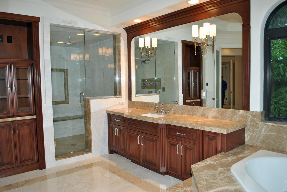 Traditional sauna bathroom in Miami with a submerged sink, raised-panel cabinets, medium wood cabinets, marble worktops, a corner bath, beige tiles and stone tiles.