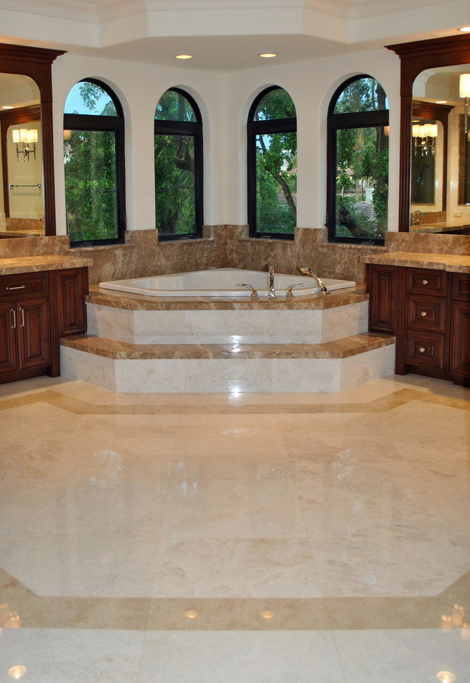 Example of a classic beige tile and stone tile corner bathtub design in Miami with an undermount sink, raised-panel cabinets, medium tone wood cabinets and marble countertops