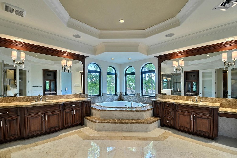 Idées déco pour une salle de bain classique en bois foncé avec un lavabo encastré, un plan de toilette en marbre, une baignoire d'angle, un carrelage beige, un carrelage de pierre et un sol en marbre.