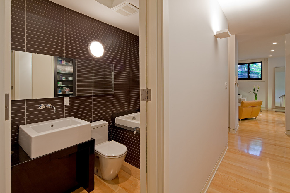 Imagen de cuarto de baño largo y estrecho actual con lavabo sobreencimera, bañera encastrada y baldosas y/o azulejos marrones