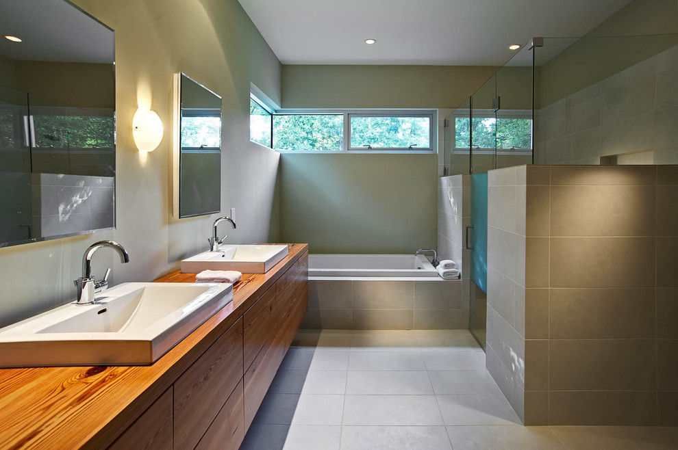 Diseño de cuarto de baño contemporáneo con lavabo encastrado, armarios con paneles lisos, puertas de armario de madera oscura, encimera de madera, bañera encastrada, ducha empotrada y baldosas y/o azulejos beige