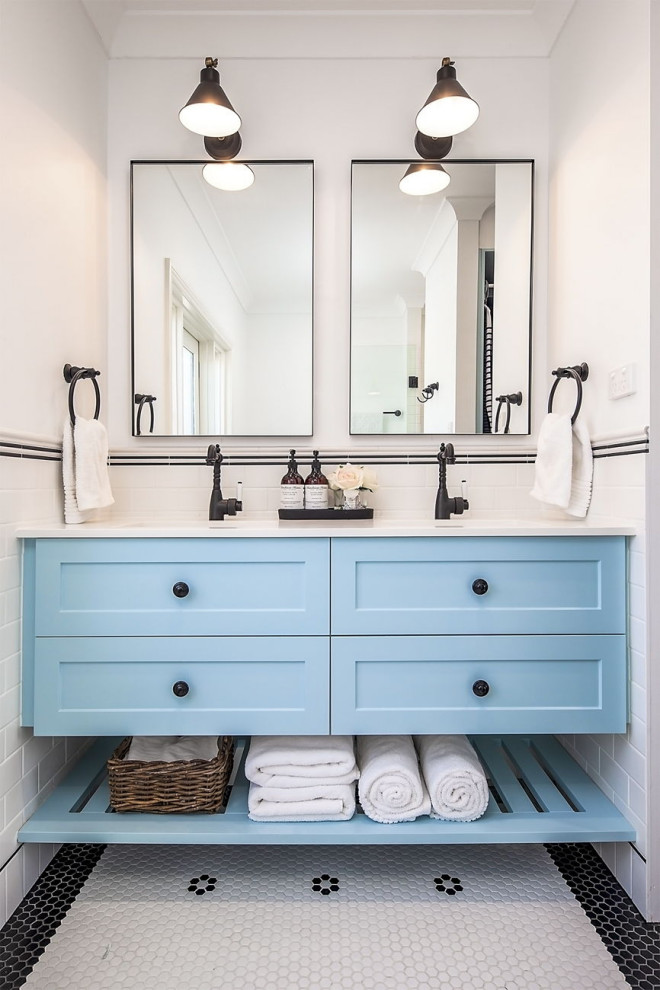 Пример оригинального дизайна: маленькая главная ванная комната в стиле неоклассика (современная классика) с фасадами в стиле шейкер, синими фасадами, душем в нише, унитазом-моноблоком, белой плиткой, керамической плиткой, белыми стенами, полом из керамической плитки, накладной раковиной, столешницей из искусственного кварца, душем с распашными дверями, белой столешницей, тумбой под две раковины, встроенной тумбой и разноцветным полом для на участке и в саду