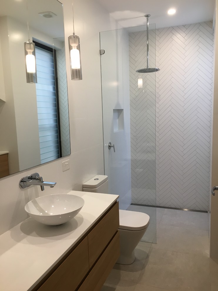 Modelo de cuarto de baño contemporáneo pequeño con puertas de armario de madera clara, ducha abierta, sanitario de una pieza, baldosas y/o azulejos blancos, baldosas y/o azulejos de porcelana, paredes blancas, suelo de baldosas de porcelana, lavabo sobreencimera, encimera de cuarzo compacto, suelo gris y ducha abierta