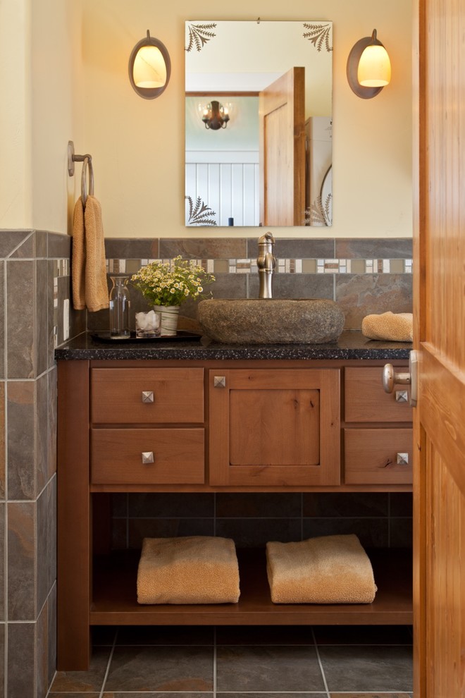 Cette photo montre une salle d'eau nature en bois brun de taille moyenne avec un placard à porte shaker, un carrelage gris, du carrelage en ardoise, un mur beige, un sol en ardoise, une vasque et un sol gris.