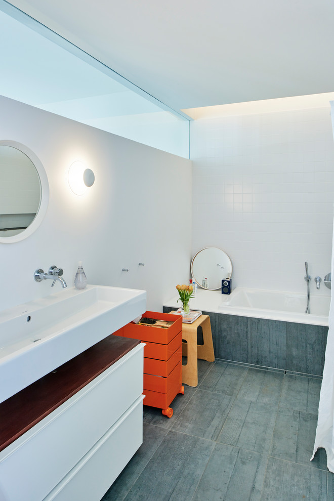 Foto di una stanza da bagno industriale con ante lisce, ante bianche, vasca da incasso, piastrelle bianche, piastrelle in ceramica, pavimento grigio e top bianco