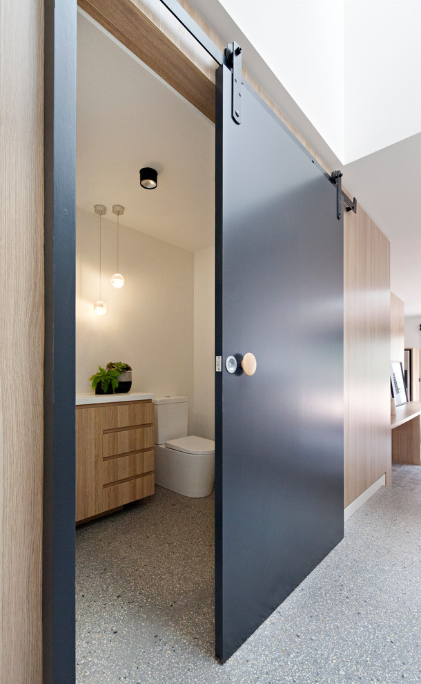 メルボルンにある小さなコンテンポラリースタイルのおしゃれな浴室 (中間色木目調キャビネット、分離型トイレ、白い壁、コンクリートの床、オーバーカウンターシンク、クオーツストーンの洗面台) の写真