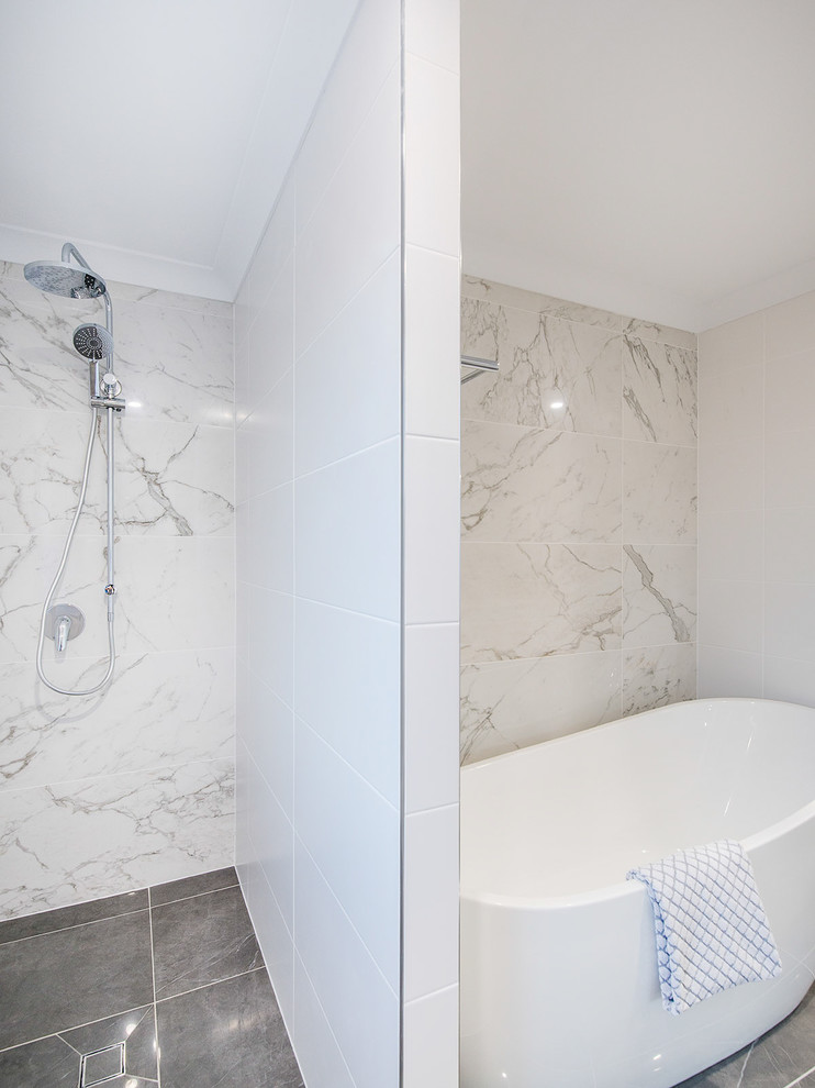 Cette image montre une salle de bain principale marine de taille moyenne avec une baignoire indépendante, une douche ouverte, un carrelage gris, des carreaux de porcelaine, un sol en carrelage de porcelaine et un sol gris.