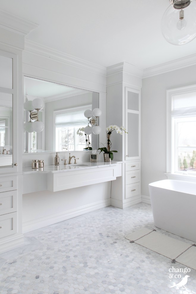 Photo of an expansive traditional ensuite bathroom in New York with shaker cabinets, white cabinets, a freestanding bath, a corner shower, white tiles, marble tiles, white walls, marble flooring, a submerged sink, marble worktops, white floors and a hinged door.