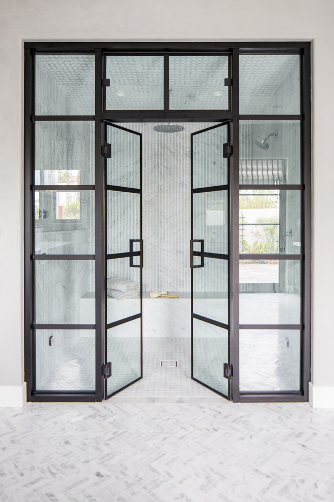 Идея дизайна: большая главная ванная комната в средиземноморском стиле с черными фасадами, отдельно стоящей ванной, душем без бортиков, белыми стенами, мраморным полом, мраморной столешницей и душем с распашными дверями