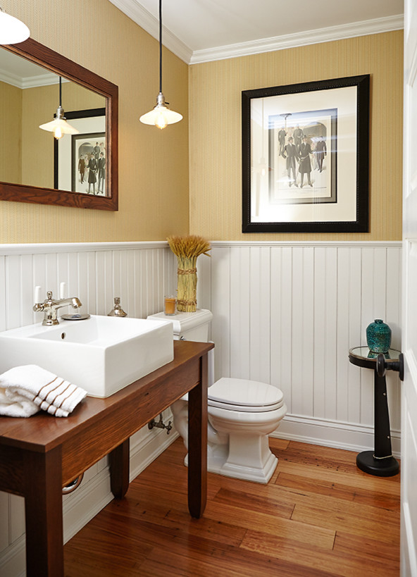 Idéer för att renovera ett lantligt brun brunt badrum, med skåp i mörkt trä, en toalettstol med separat cisternkåpa, gula väggar, mellanmörkt trägolv, ett fristående handfat, träbänkskiva och brunt golv