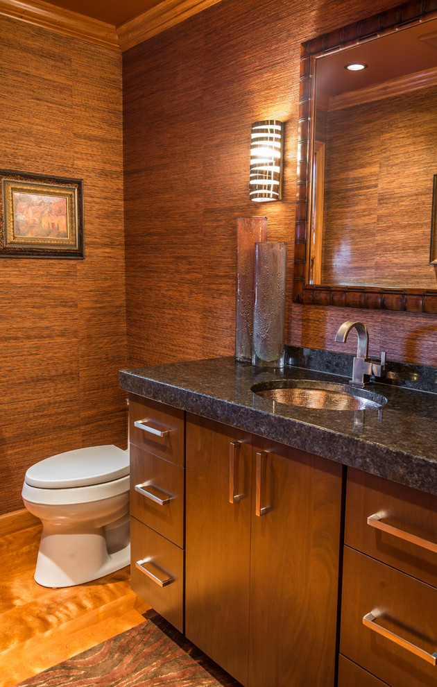 Foto de cuarto de baño actual pequeño con lavabo bajoencimera, armarios con paneles lisos, puertas de armario de madera en tonos medios, encimera de granito y suelo de madera clara
