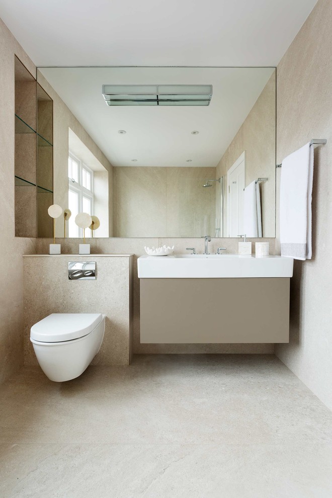 Modernes Duschbad mit flächenbündigen Schrankfronten, beigen Schränken, Wandtoilette, beigen Fliesen, beiger Wandfarbe, integriertem Waschbecken, beigem Boden und weißer Waschtischplatte in London