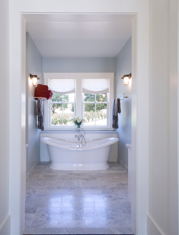 Idée de décoration pour une salle de bain principale champêtre de taille moyenne avec un placard à porte shaker, des portes de placard blanches, une baignoire indépendante, un carrelage beige, un carrelage gris, un carrelage de pierre, un mur bleu, un sol en marbre, un lavabo encastré et un plan de toilette en quartz modifié.