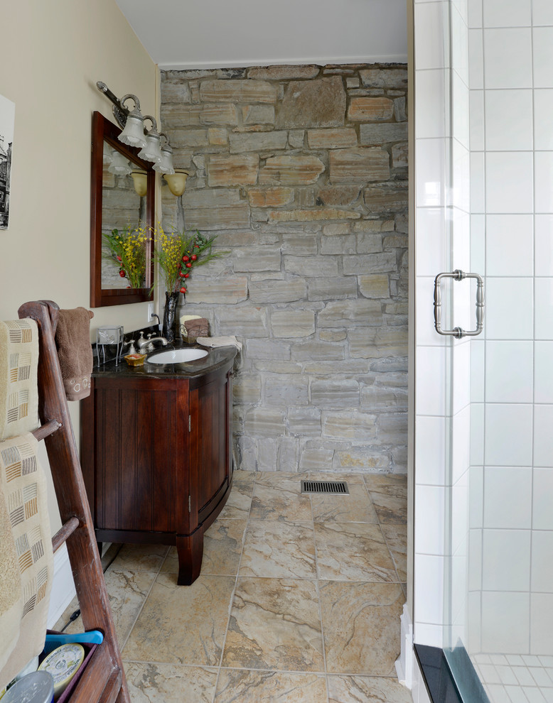 Immagine di una piccola stanza da bagno con doccia country con lavabo sottopiano, ante con bugna sagomata, ante in legno scuro, top in granito, doccia alcova, piastrelle grigie, piastrelle in pietra, pareti beige e pavimento in ardesia