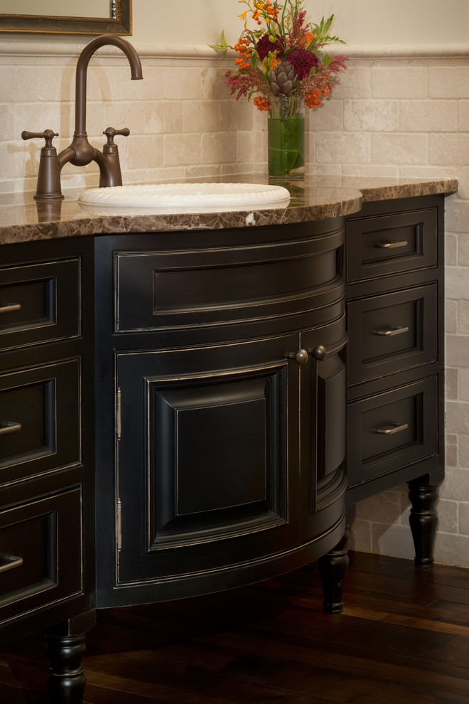 Klassisches Badezimmer mit verzierten Schränken, schwarzen Schränken, beigen Fliesen, beiger Wandfarbe, dunklem Holzboden und brauner Waschtischplatte in Denver