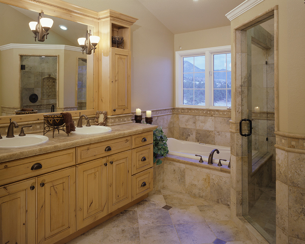 Modelo de cuarto de baño principal rural grande con lavabo encastrado, armarios con paneles con relieve, puertas de armario con efecto envejecido, encimera de azulejos, bañera encastrada, ducha esquinera, baldosas y/o azulejos beige y paredes beige