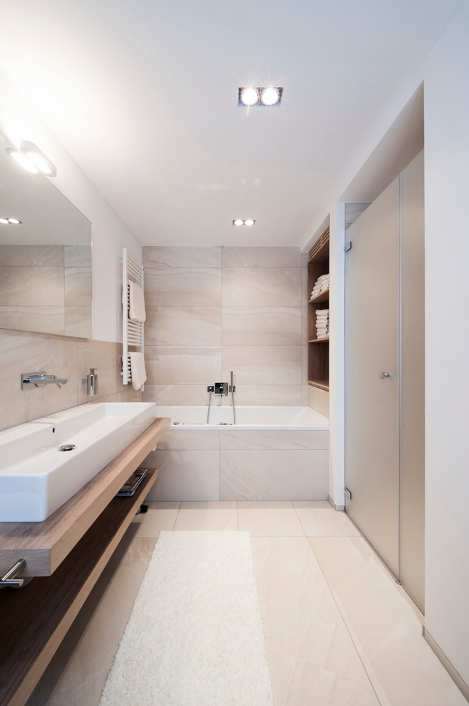 アムステルダムにある高級な小さなラスティックスタイルのおしゃれなマスターバスルーム (落し込みパネル扉のキャビネット、淡色木目調キャビネット、大型浴槽、ベージュのタイル、セラミックタイル、木製洗面台) の写真
