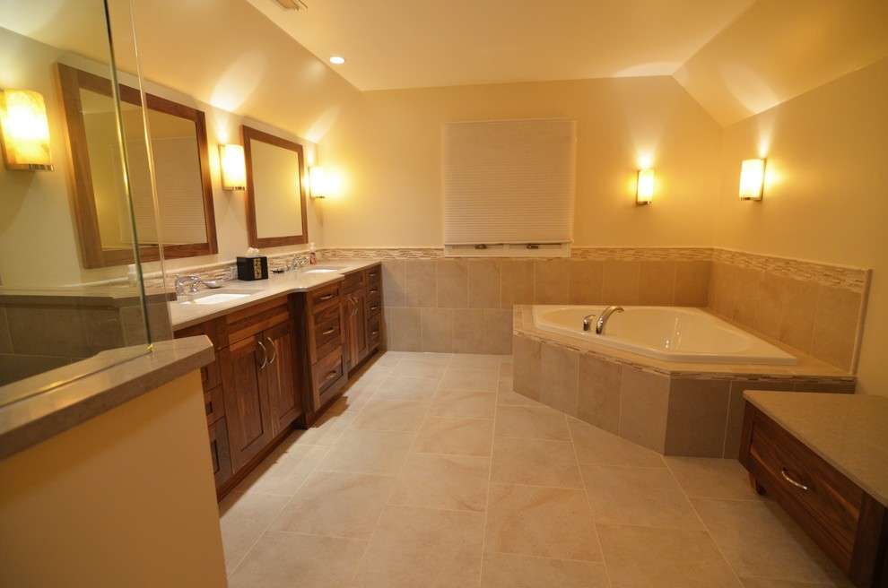 Klassisk inredning av ett badrum, med ett undermonterad handfat, skåp i shakerstil, skåp i mellenmörkt trä, bänkskiva i kvarts, ett platsbyggt badkar, en hörndusch, en toalettstol med separat cisternkåpa, beige kakel och porslinskakel