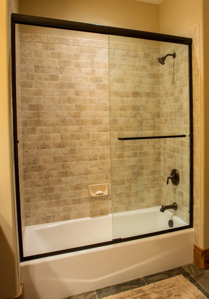 Exempel på ett mellanstort amerikanskt badrum med dusch, med ett integrerad handfat, luckor med upphöjd panel, skåp i mörkt trä, bänkskiva i akrylsten, ett badkar i en alkov, en dusch/badkar-kombination, en toalettstol med hel cisternkåpa, flerfärgad kakel, stenkakel, gula väggar och skiffergolv