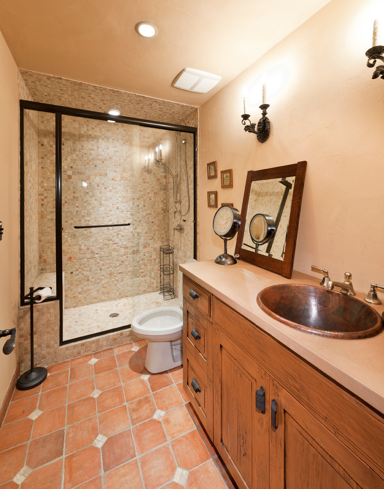 Cette image montre une salle de bain chalet avec un lavabo posé et tomettes au sol.