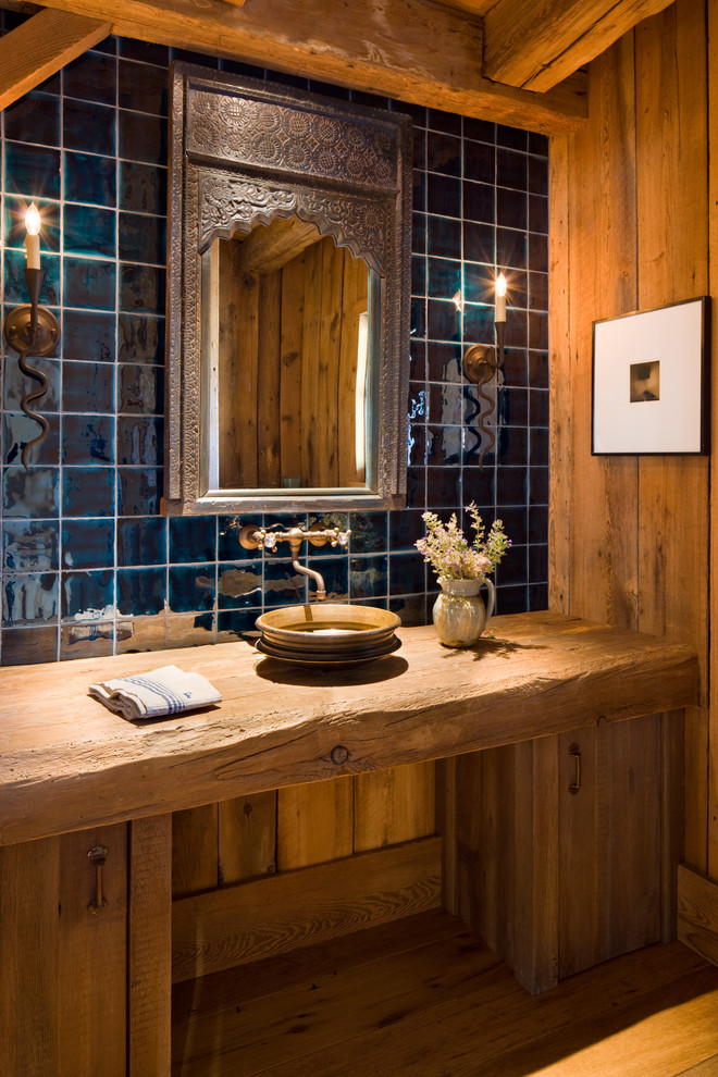 Rustikales Badezimmer mit Aufsatzwaschbecken, flächenbündigen Schrankfronten, hellbraunen Holzschränken, blauen Fliesen, Keramikfliesen und braunem Holzboden in Sonstige