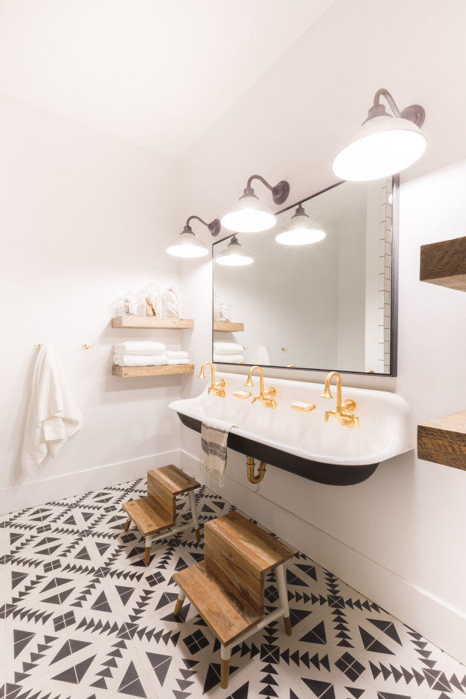 Modelo de cuarto de baño rural con puertas de armario blancas, paredes blancas, suelo de azulejos de cemento, lavabo suspendido y suelo multicolor