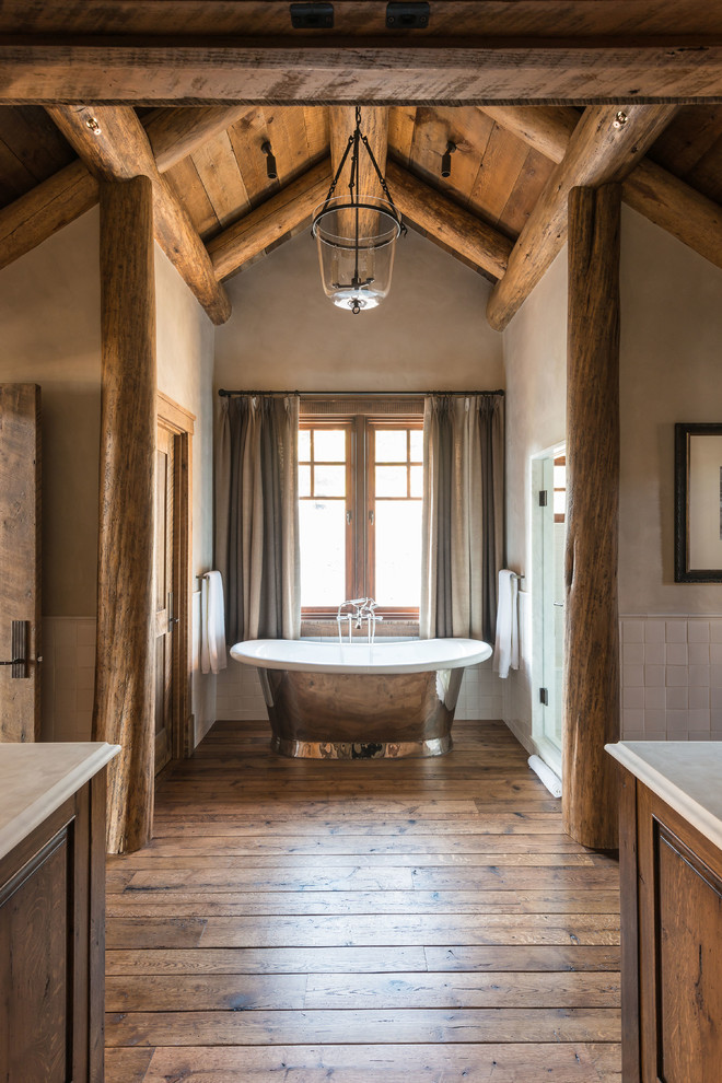 На фото: ванная комната в стиле рустика с отдельно стоящей ванной, белой плиткой, коричневыми стенами и темным паркетным полом