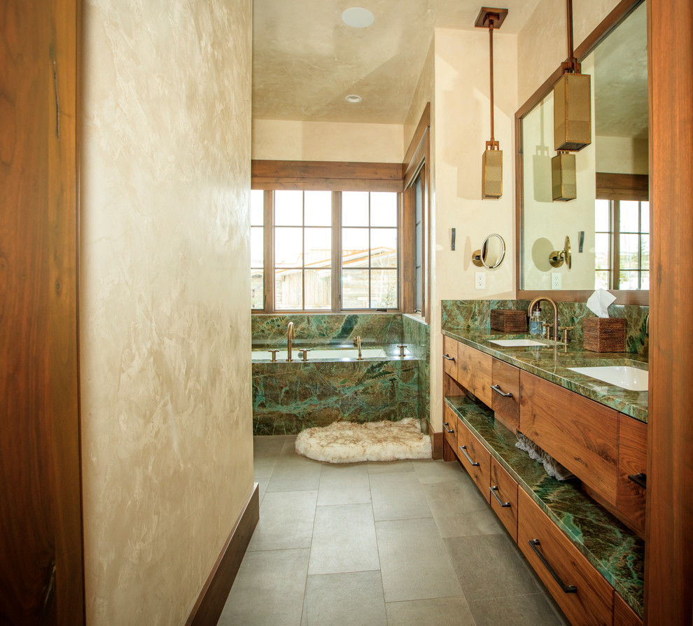 Imagen de cuarto de baño rústico con armarios con paneles lisos, puertas de armario de madera oscura, bañera encastrada sin remate, paredes beige, lavabo bajoencimera, suelo gris y encimeras verdes