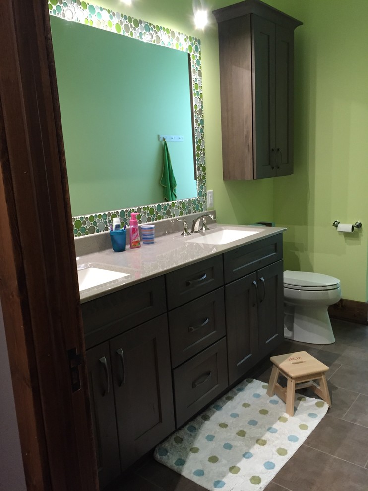 Diseño de cuarto de baño infantil tradicional renovado de tamaño medio con lavabo integrado, armarios estilo shaker, puertas de armario de madera en tonos medios, encimera de ónix, baldosas y/o azulejos verdes, paredes verdes y suelo de baldosas de porcelana