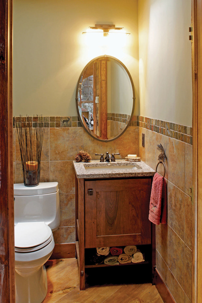 Cette image montre une petite salle d'eau craftsman en bois brun avec un placard à porte shaker, WC à poser, un carrelage multicolore, un carrelage de pierre, un mur beige, un sol en bois brun, un lavabo encastré et un plan de toilette en quartz modifié.