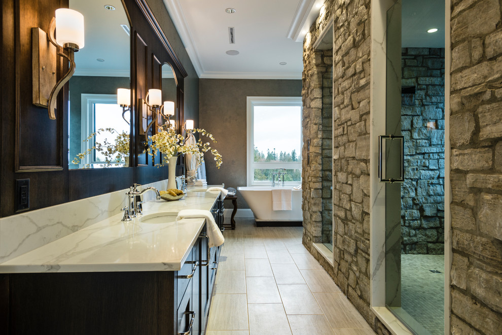 Photo of an expansive rustic ensuite wet room bathroom in Vancouver with shaker cabinets, dark wood cabinets, a freestanding bath, a two-piece toilet, grey tiles, stone tiles, grey walls, porcelain flooring, a submerged sink, solid surface worktops, grey floors, a hinged door and white worktops.