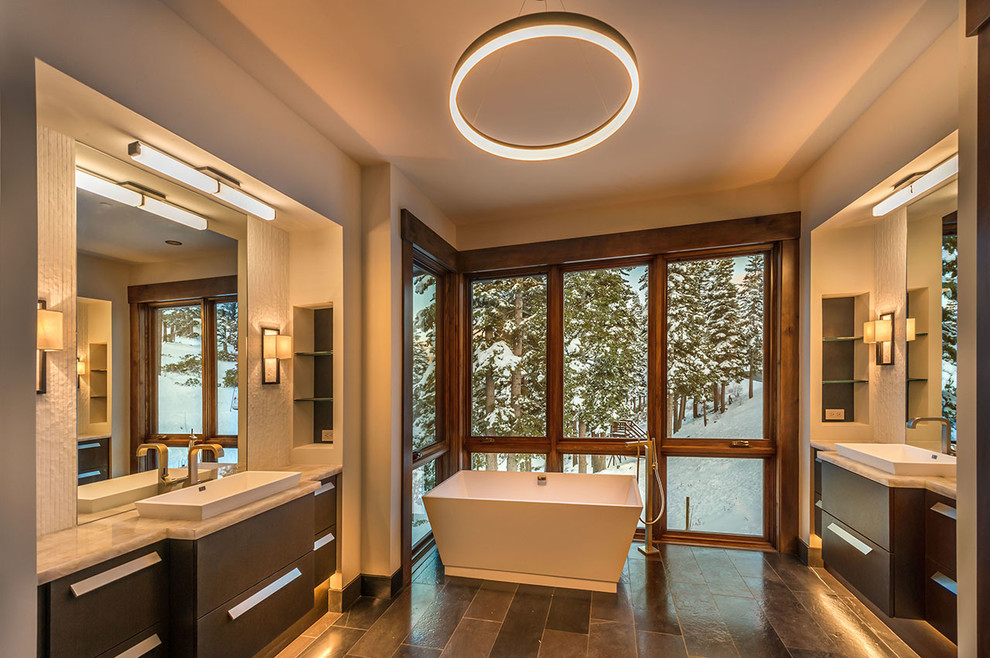 Large rustic ensuite bathroom in Other with flat-panel cabinets, dark wood cabinets, a freestanding bath, brown tiles, stone tiles, beige walls, slate flooring, a vessel sink and engineered stone worktops.