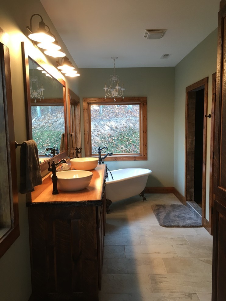 Cette image montre une salle de bain principale chalet en bois brun de taille moyenne avec un placard avec porte à panneau encastré, une baignoire sur pieds, une vasque, WC à poser et un mur vert.