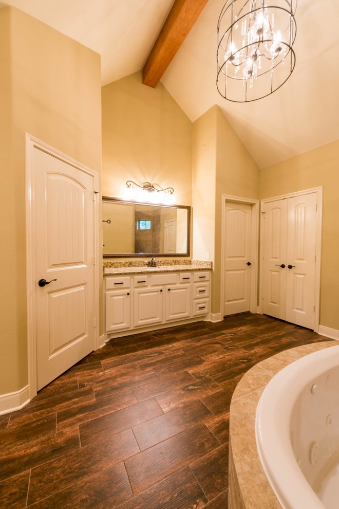 Mid-sized arts and crafts master beige tile and stone tile dark wood floor bathroom photo in Houston with raised-panel cabinets, white cabinets, beige walls, an undermount sink and granite countertops
