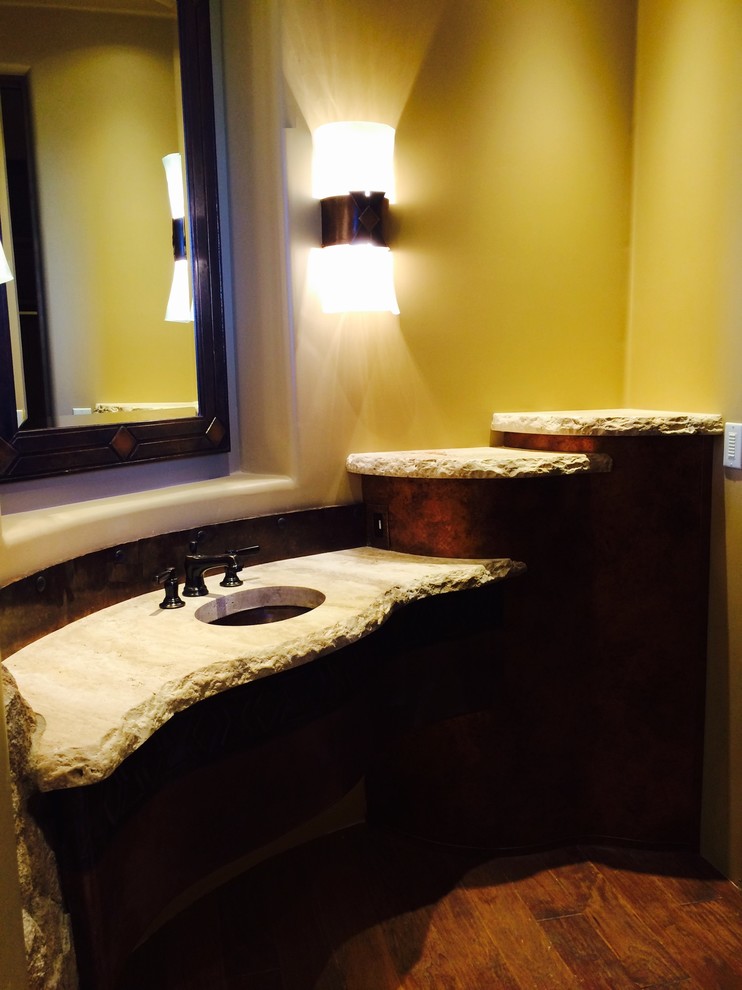 Immagine di una stanza da bagno padronale rustica di medie dimensioni con lavabo sottopiano, ante lisce, ante in legno bruno, top in pietra calcarea, piastrelle beige, piastrelle in pietra, pareti beige e pavimento in legno massello medio