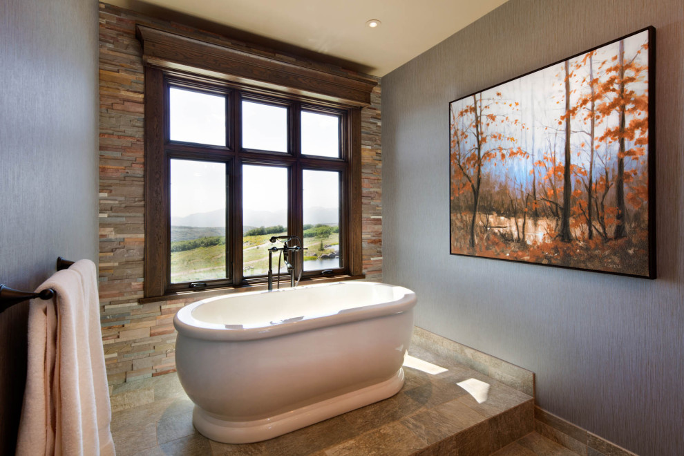 Modelo de cuarto de baño rústico con bañera exenta, paredes grises y suelo marrón
