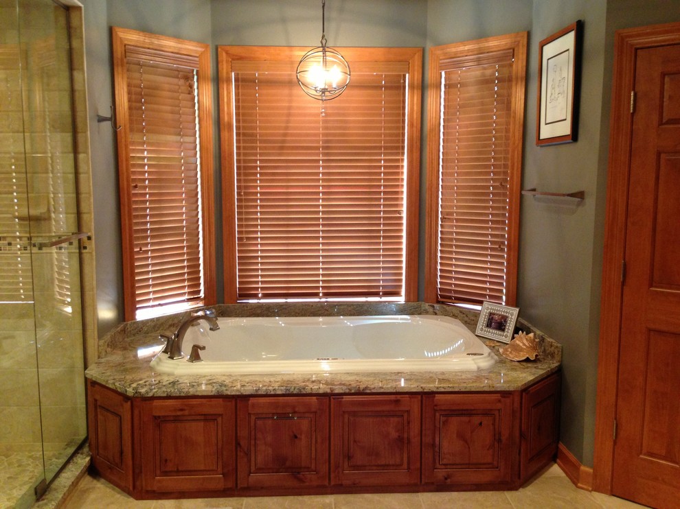 Imagen de cuarto de baño rural con armarios con paneles con relieve, puertas de armario con efecto envejecido, encimera de granito, bañera encastrada y ducha esquinera