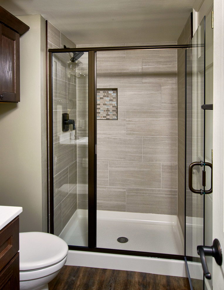Example of a mid-sized mountain style 3/4 beige tile and slate tile vinyl floor and brown floor alcove shower design in St Louis with beaded inset cabinets, brown cabinets, a one-piece toilet, gray walls, solid surface countertops and a hinged shower door