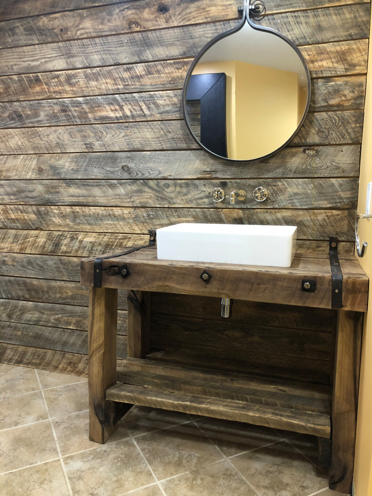 Inredning av ett lantligt mellanstort brun brunt badrum, med skåp i slitet trä, en toalettstol med hel cisternkåpa, beige kakel, travertinkakel, klinkergolv i keramik, ett konsol handfat, träbänkskiva, beiget golv och dusch med skjutdörr