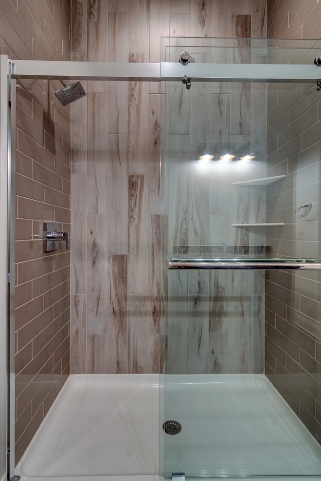 Inspiration for a large farmhouse shower room bathroom in Indianapolis with shaker cabinets, black cabinets, a built-in shower, a one-piece toilet, brown tiles, ceramic tiles, white walls, ceramic flooring, a built-in sink, grey floors and a sliding door.