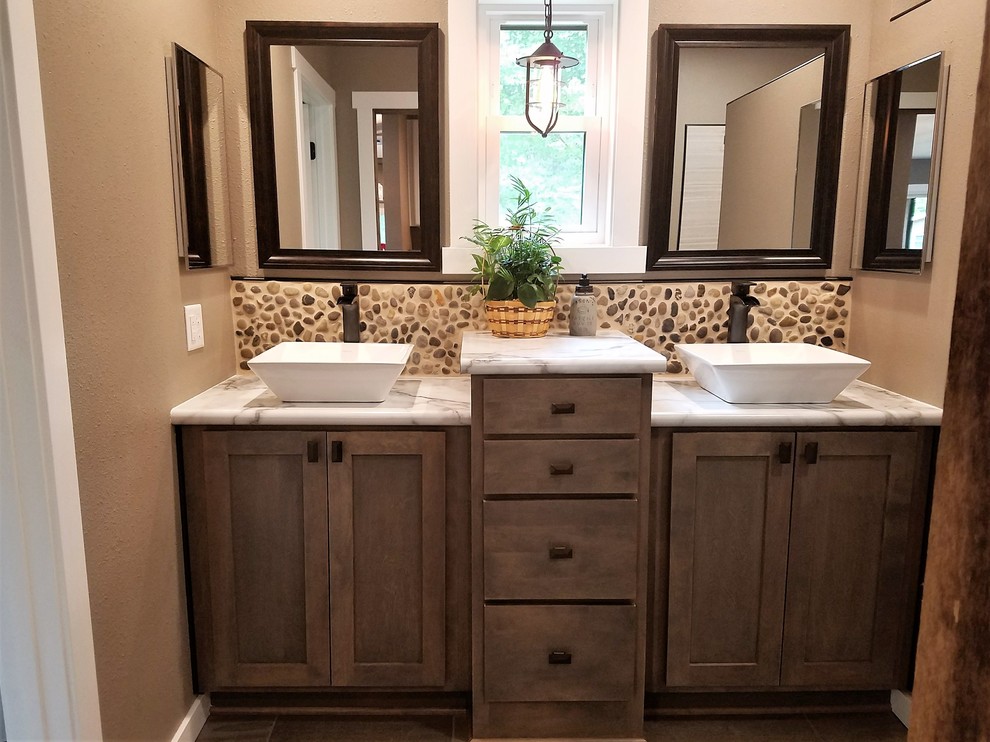 Inspiration for a mid-sized farmhouse master pebble tile, beige tile and brown tile medium tone wood floor and brown floor bathroom remodel in Other with shaker cabinets, gray cabinets, a vessel sink, laminate countertops, beige walls and beige countertops