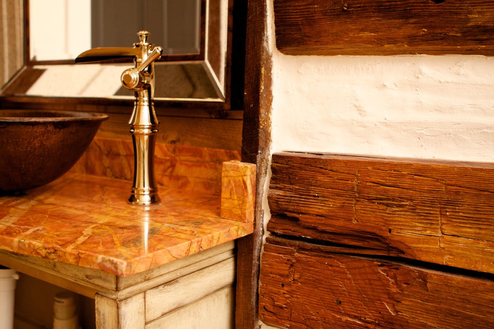 Diseño de cuarto de baño infantil campestre de tamaño medio con lavabo sobreencimera, bañera encastrada, baldosas y/o azulejos multicolor, paredes marrones, suelo de madera en tonos medios, combinación de ducha y bañera, armarios tipo mueble, puertas de armario con efecto envejecido, encimera de mármol y sanitario de dos piezas