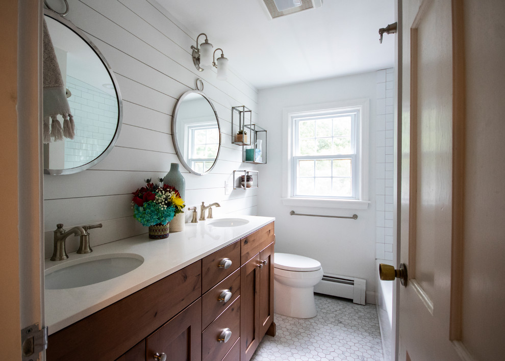 Example of a mid-sized farmhouse master white tile and porcelain tile mosaic tile floor and white floor bathroom design in Providence with recessed-panel cabinets, medium tone wood cabinets, a two-piece toilet, white walls, an undermount sink, quartz countertops, a hinged shower door and white countertops