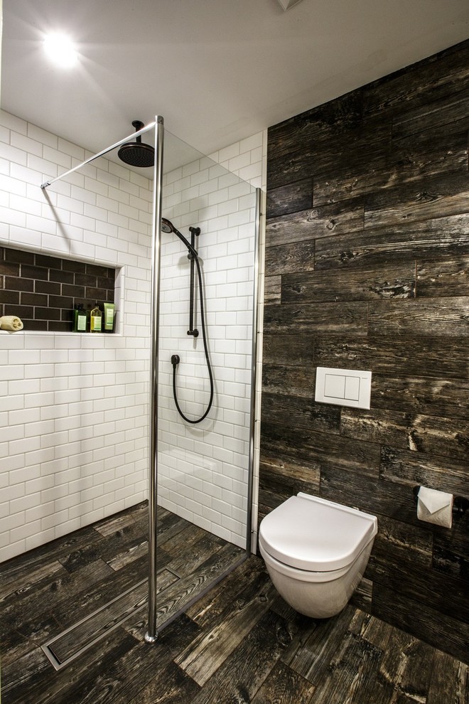 Réalisation d'une petite salle de bain principale chalet avec une douche à l'italienne, WC suspendus et parquet foncé.