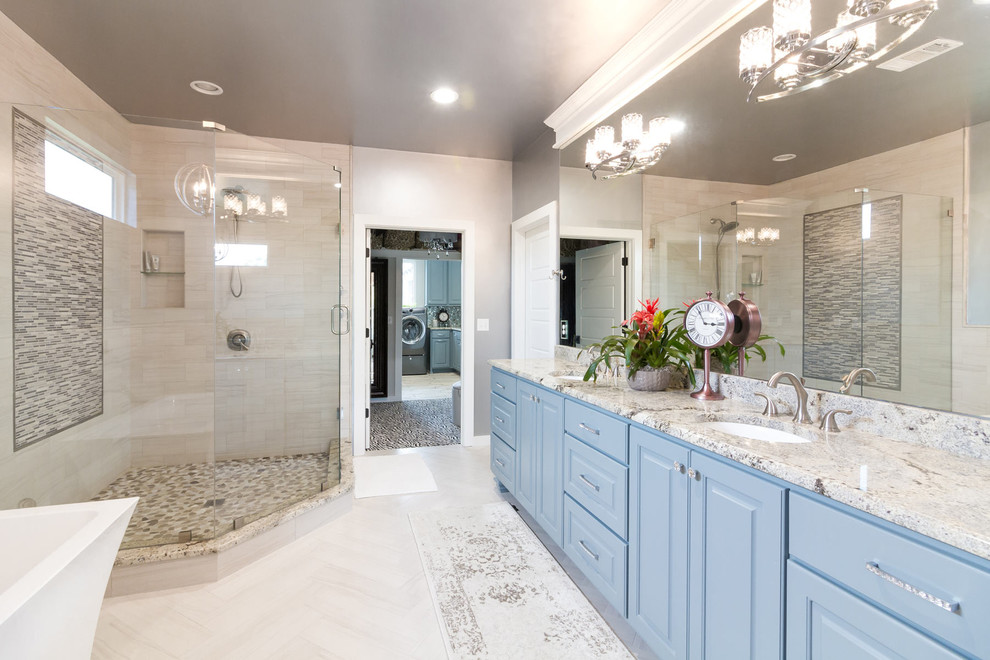 Lantlig inredning av ett en-suite badrum, med blå skåp, ett fristående badkar, grå kakel, glaskakel, grå väggar, klinkergolv i porslin, grått golv och dusch med gångjärnsdörr