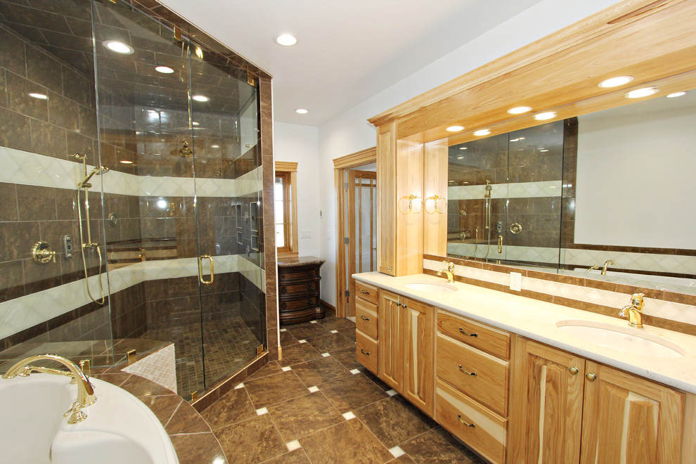 Photo of an expansive traditional bathroom in Boise with raised-panel cabinets, light wood cabinets, a corner bath, a built-in shower, a one-piece toilet, beige tiles, ceramic tiles, white walls, ceramic flooring, a submerged sink and granite worktops.