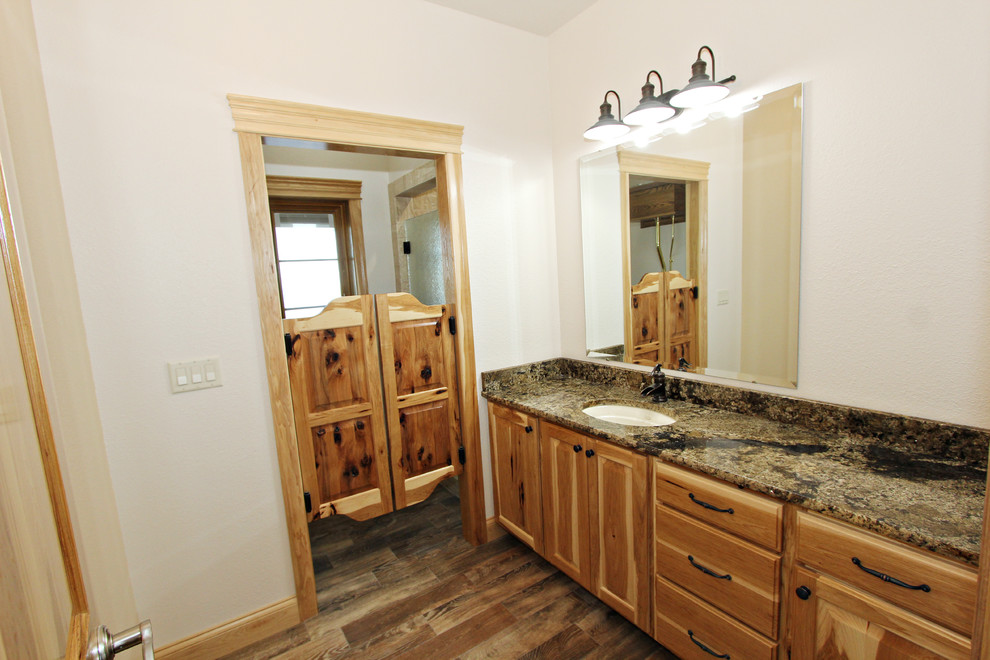 Inspiration pour une grande salle de bain chalet en bois clair avec un placard avec porte à panneau surélevé, un mur beige, un sol en bois brun, un lavabo encastré et un plan de toilette en granite.