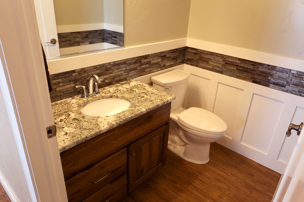 Cette photo montre une petite salle de bain montagne en bois foncé avec un placard à porte plane, WC à poser, un mur beige, un sol en bois brun, un lavabo encastré et un plan de toilette en granite.