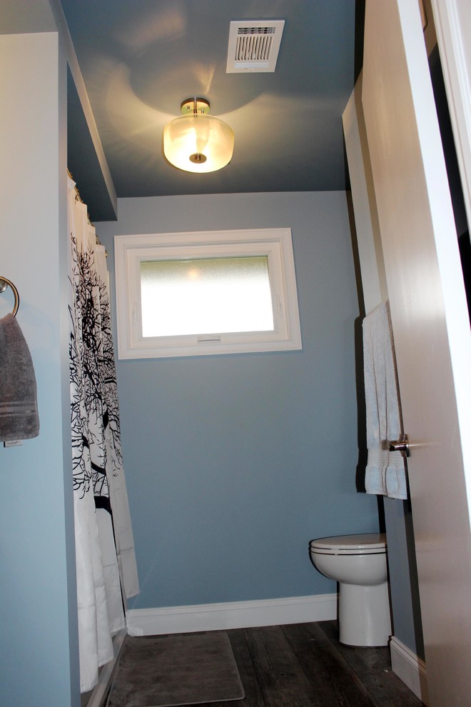 Aménagement d'une salle de bain principale montagne en bois foncé de taille moyenne avec un combiné douche/baignoire, WC à poser, un mur bleu, parquet clair, un lavabo encastré et un plan de toilette en marbre.