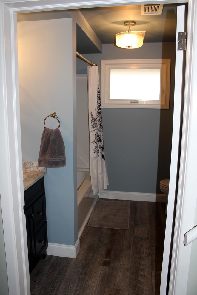 Cette photo montre une salle de bain principale montagne en bois foncé de taille moyenne avec un combiné douche/baignoire, WC à poser, un mur bleu, parquet clair, un lavabo encastré et un plan de toilette en marbre.